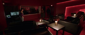 Movie still from “M3GAN” (2022), directed by Gerard Johnstone – Two men are standing in a room with a red wall; Wide shot, High angle