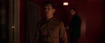 Movie still from “M3GAN” (2022), directed by Gerard Johnstone – A man standing in a dark room next to another man; Medium shot, Over the shoulder angle