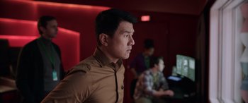 Movie still from “M3GAN” (2022), directed by Gerard Johnstone – A man in a brown shirt looking to his left; Medium shot, Over the shoulder angle