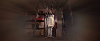 Movie still from “M3GAN” (2022), directed by Gerard Johnstone – A woman standing in a room with wires hanging from the ceiling; Wide shot, Low angle