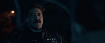 Movie still from “M3GAN” (2022), directed by Gerard Johnstone – A man in a black police uniform with a mustache; Close Up shot, Over the shoulder angle