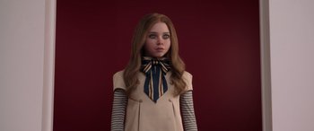 Movie still from “M3GAN” (2022), directed by Gerard Johnstone – A girl with long brown hair wearing a dress and a striped tie; Close Up shot, High angle