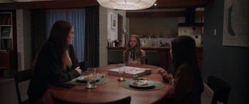 Movie still from “M3GAN” (2022), directed by Gerard Johnstone – A woman sitting at a table in front of two other people; Wide shot, Over the shoulder angle