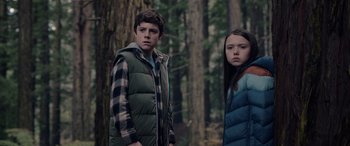 Movie still from “M3GAN” (2022), directed by Gerard Johnstone – A boy and a girl standing next to each other in the woods; Medium shot, Low angle