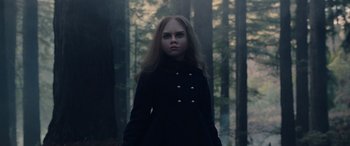 Movie still from “M3GAN” (2022), directed by Gerard Johnstone – A woman in a black coat standing in the woods; Close Up shot, Low angle