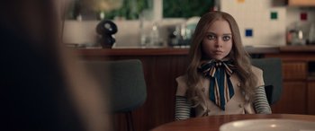 Movie still from “M3GAN” (2022), directed by Gerard Johnstone – A girl sitting at a table in front of a chair; Close Up shot, Over the shoulder angle