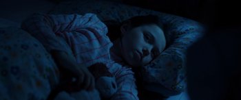 Movie still from “M3GAN” (2022), directed by Gerard Johnstone – A little girl laying in a bed with a teddy bear; Close Up shot, High angle
