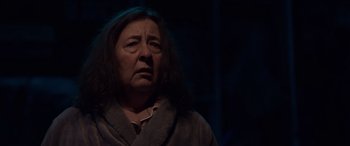 Movie still from “M3GAN” (2022), directed by Gerard Johnstone – An older woman with long black hair looking sad; Close Up shot, Over the shoulder angle