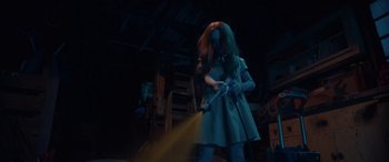 Movie still from “M3GAN” (2022), directed by Gerard Johnstone – A woman in a blue dress holding a yellow hose; Medium shot, Low angle