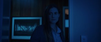 Movie still from “M3GAN” (2022), directed by Gerard Johnstone – A woman standing in the dark in front of a wall; Medium shot, Over the shoulder angle