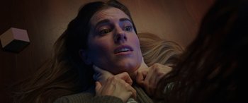 Movie still from “M3GAN” (2022), directed by Gerard Johnstone – A woman laying on the ground with her hands on her neck; Close Up shot, Overhead angle