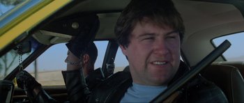 Movie still from “Mad Max” (1979), directed by George Miller – A man in the passenger seat of a car; Close Up shot, Low angle
