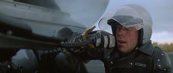 Movie still from “Mad Max” (1979), directed by George Miller – A man in a leather jacket holding a gun; Close Up shot, Low angle