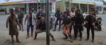 Movie still from “Mad Max” (1979), directed by George Miller – A group of men in leather jackets posing for a picture; Wide shot, Low angle