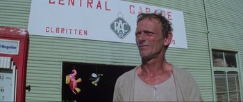 Movie still from “Mad Max” (1979), directed by George Miller – A man standing in front of a garage door; Close Up shot, Low angle
