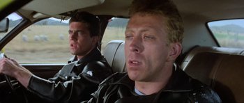 Movie still from “Mad Max” (1979), directed by George Miller – Two men in the back seat of a car; Close Up shot, Low angle