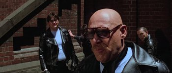 Movie still from “Mad Max” (1979), directed by George Miller – A man with a bald head wearing a leather jacket; Close Up shot, Low angle