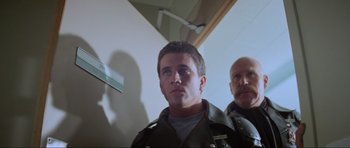 Movie still from “Mad Max” (1979), directed by George Miller – A man in a police uniform standing next to another man; Close Up shot, Low angle