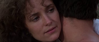 Movie still from “Mad Max” (1979), directed by George Miller – A woman's face with her head resting on the shoulder of a man; Close Up shot, Over the shoulder angle