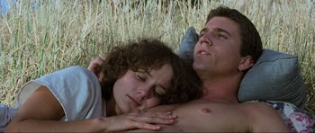 Movie still from “Mad Max” (1979), directed by George Miller – A man and a woman laying in a field; Close Up shot, Low angle