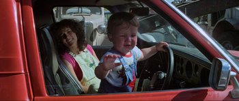 Movie still from “Mad Max” (1979), directed by George Miller – A young child in the driver's seat of a car; Medium shot, High angle