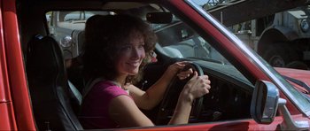 Movie still from “Mad Max” (1979), directed by George Miller – A woman sitting in the driver's seat of a red car; Close Up shot, Low angle