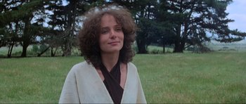 Movie still from “Mad Max” (1979), directed by George Miller – A woman in a white jacket standing in the grass; Close Up shot, Low angle