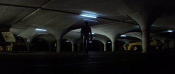 Movie still from “Mad Max” (1979), directed by George Miller – A person walking in a parking garage at night; Extreme Wide shot, Low angle