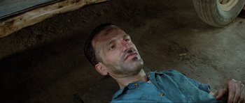 Movie still from “Mad Max” (1979), directed by George Miller – A person wearing a blue shirt; Close Up shot, Overhead angle