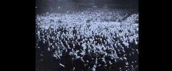Movie still from “The Road Warrior” (1981), directed by George Miller – A large group of people are gathered together in a stadium; Extreme Wide shot, High angle
