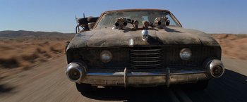 Movie still from “The Road Warrior” (1981), directed by George Miller – An old car with a bunch of guns on it's hood; Wide shot, Low angle