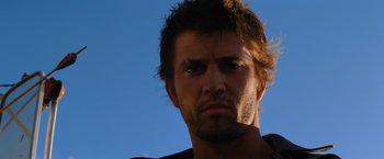 Movie still from “The Road Warrior” (1981), directed by George Miller – A man's face in the sunlight; Close Up shot, Low angle