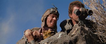 Movie still from “The Road Warrior” (1981), directed by George Miller – A man in a helmet is holding a knife; Close Up shot, Low angle