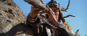 Movie still from “The Road Warrior” (1981), directed by George Miller – An old man holding a telescope and talking on a cell phone; Close Up shot, Low angle
