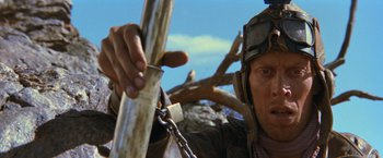 Movie still from “The Road Warrior” (1981), directed by George Miller – A person holding a metal pole; Close Up shot, Low angle