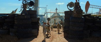Movie still from “The Road Warrior” (1981), directed by George Miller – A group of people walking down a dirt road; Extreme Wide shot, Low angle
