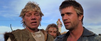 Movie still from “The Road Warrior” (1981), directed by George Miller – A group of people standing next to each other on top of a hill; Close Up shot, Low angle