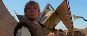 Movie still from “The Road Warrior” (1981), directed by George Miller – A man standing in front of a building; Close Up shot, Low angle