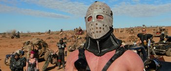 Movie still from “The Road Warrior” (1981), directed by George Miller – A man with a helmet and a leather mask on; Close Up shot, Low angle