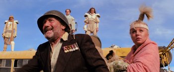 Movie still from “The Road Warrior” (1981), directed by George Miller – A group of people standing on top of a hill; Medium shot, Low angle