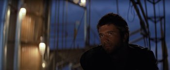 Movie still from “The Road Warrior” (1981), directed by George Miller – A person wearing a black shirt; Close Up shot, Over the shoulder angle