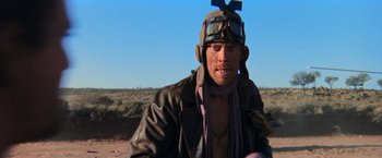 Movie still from “The Road Warrior” (1981), directed by George Miller – A man wearing a leather jacket and a hat; Close Up shot, Low angle