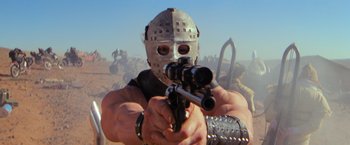 Movie still from “The Road Warrior” (1981), directed by George Miller – A man wearing a mask and holding a gun; Close Up shot, Low angle