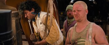 Movie still from “The Road Warrior” (1981), directed by George Miller – A group of men standing next to each other; Medium shot, Over the shoulder angle