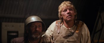 Movie still from “The Road Warrior” (1981), directed by George Miller – Two men in medieval garb posing for a picture; Close Up shot, Low angle