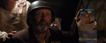 Movie still from “The Road Warrior” (1981), directed by George Miller – An older man wearing a helmet and a beard; Close Up shot, Over the shoulder angle