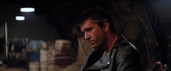 Movie still from “The Road Warrior” (1981), directed by George Miller – A person wearing a leather jacket; Close Up shot, Over the shoulder angle