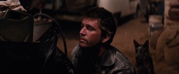 Movie still from “The Road Warrior” (1981), directed by George Miller – A person sitting on the ground; Close Up shot, Low angle