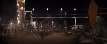 Movie still from “The Road Warrior” (1981), directed by George Miller – A group of men working in a garage at night; Extreme Wide shot, High angle