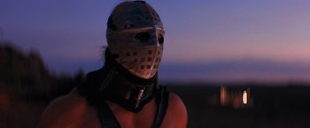 Movie still from “The Road Warrior” (1981), directed by George Miller – A man wearing a metal mask and leather vest; Close Up shot, Low angle